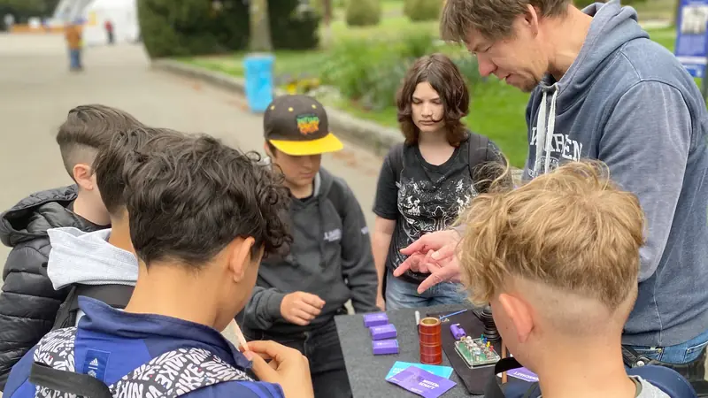 Markus Pfeil zeigt Jugendlichen am Stand bei Explore Science 2025 einen Zaubertrick